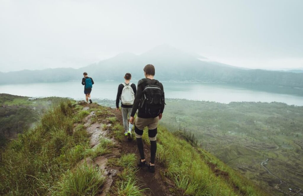 Three hikers walk a trail with a misty mountainous backdrop